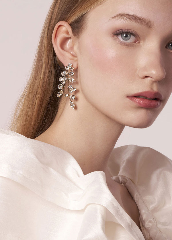 Close-up of a woman wearing a pair of diamond earrings with a soft background