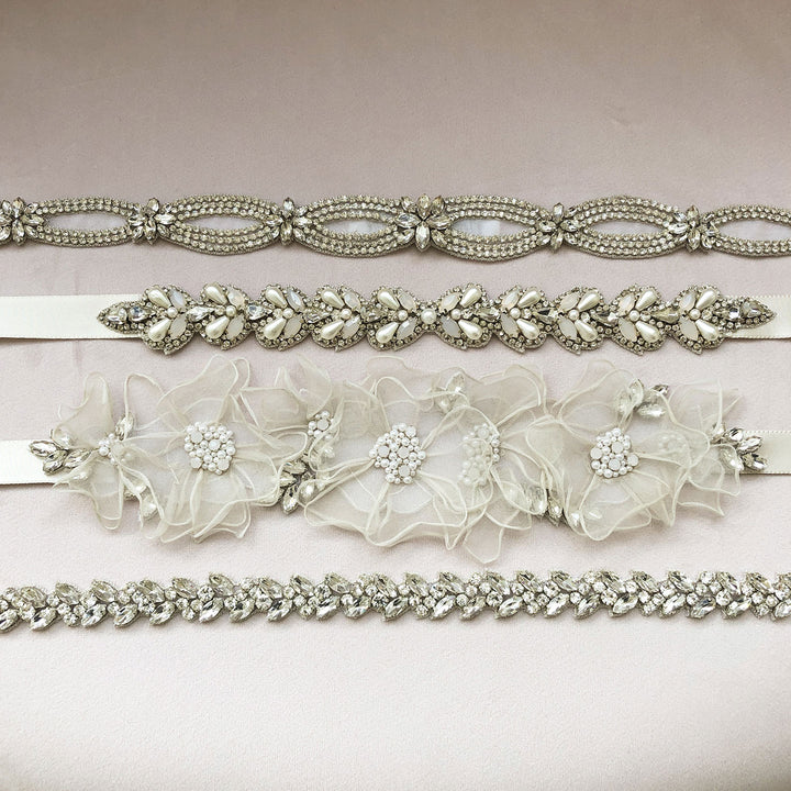 A selection of embroidered wedding dress belts laid flat on pink velvet