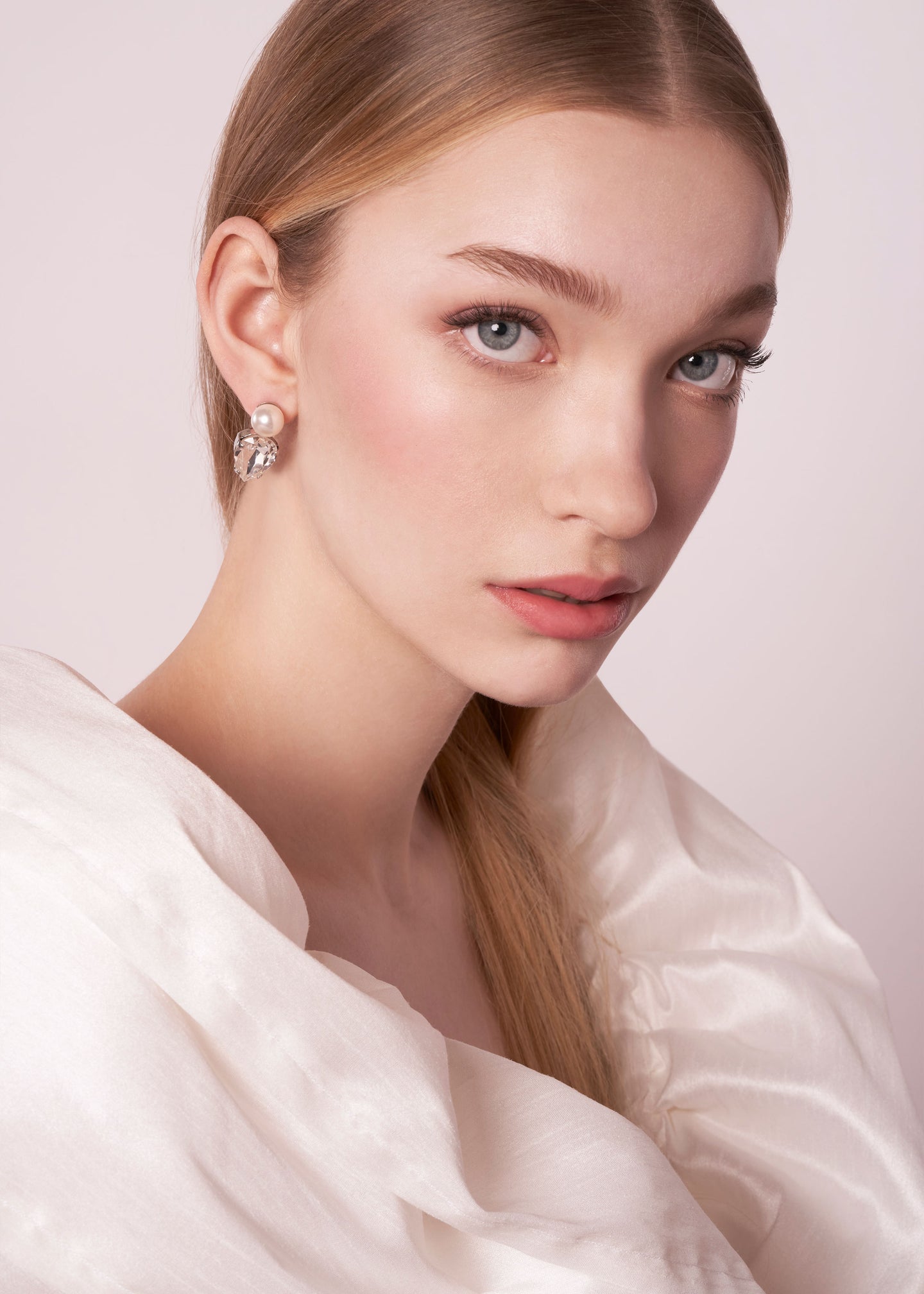 Teardrop Crystal and pearl bridal stud earring on model in ruffled wedding dress (portrait side view)