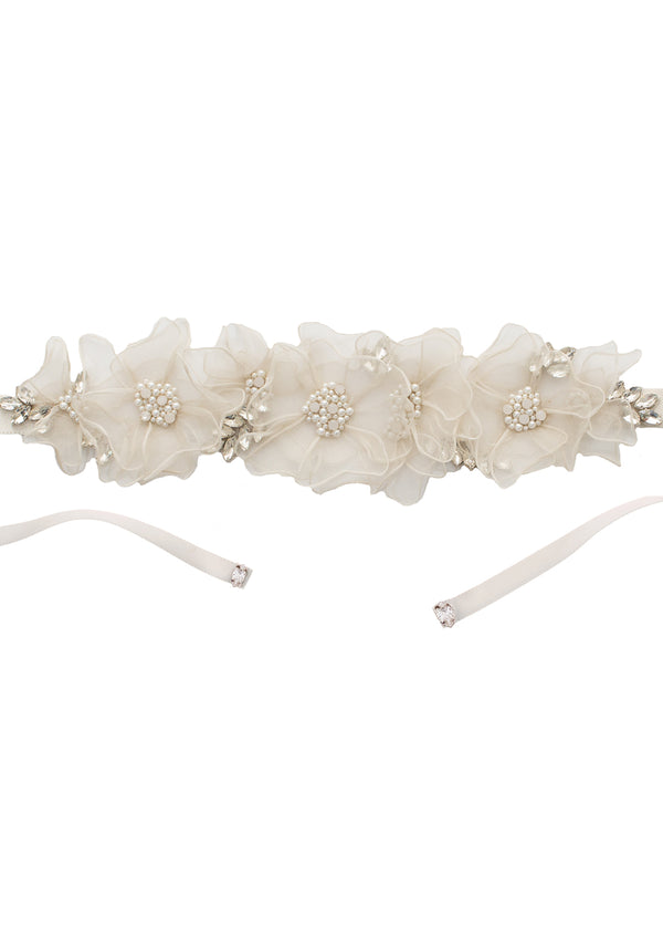 Floral silk wedding dress sash with crystal and pearls centers on a laid flat white background 