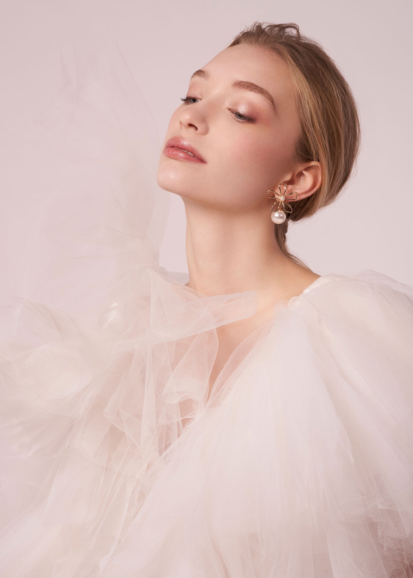 Gold open flower and pearl stud earring on model in tulle dress