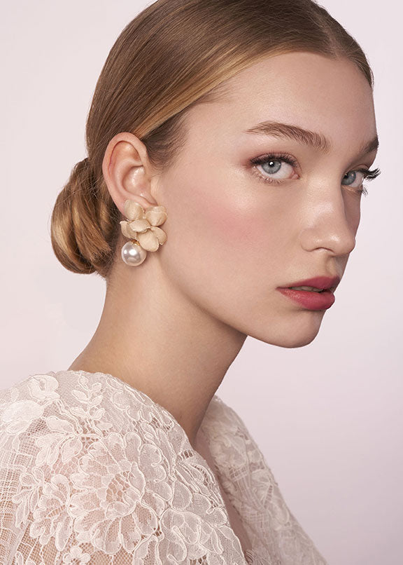 portrait image of a silk and pearl gold floral bridal stud earring on model in a lace puff sleeve dress