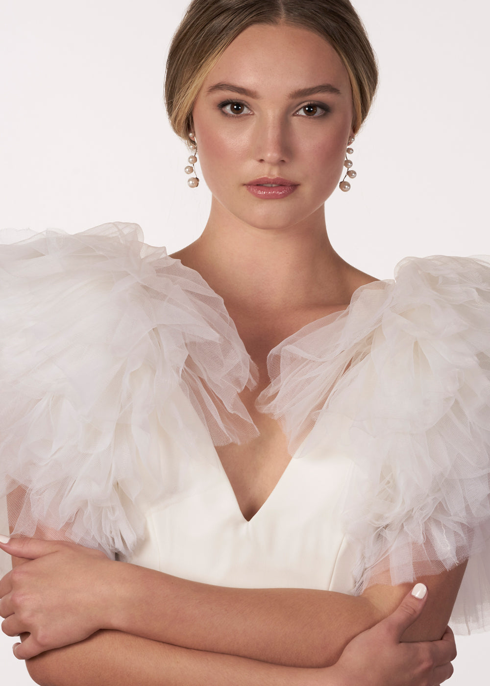 A modern linear silver pearl earring with 5 graduating pearls on a model in a tulle wedding dress (front view)