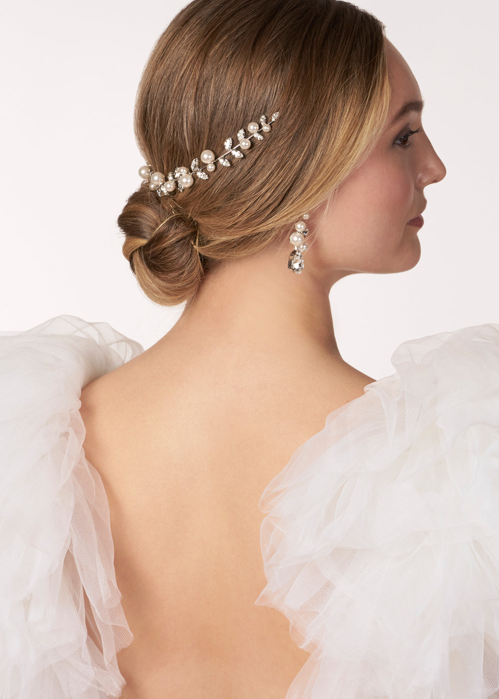 Golden pearl and crystal garland wedding hairpiece on a model  in a tulle wedding dress (back view looking to the side)